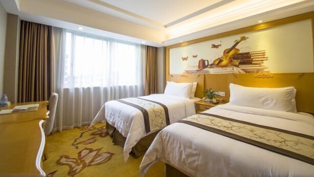 Une chambre d’hôtel avec deux lits, un bureau et une grande fenêtre.