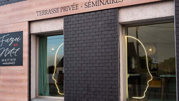Eine Gebäudefassade mit einem Schild für 'Terrasse Privée - Séminaires - Salle de Salles' und einem Schild für 'Fuzei Hotel' darunter.