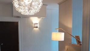 Ein modernes Wohnzimmer mit zwei Sesseln, einem runden Couchtisch, einer Stehlampe und einer dekorativen Deckenleuchte.