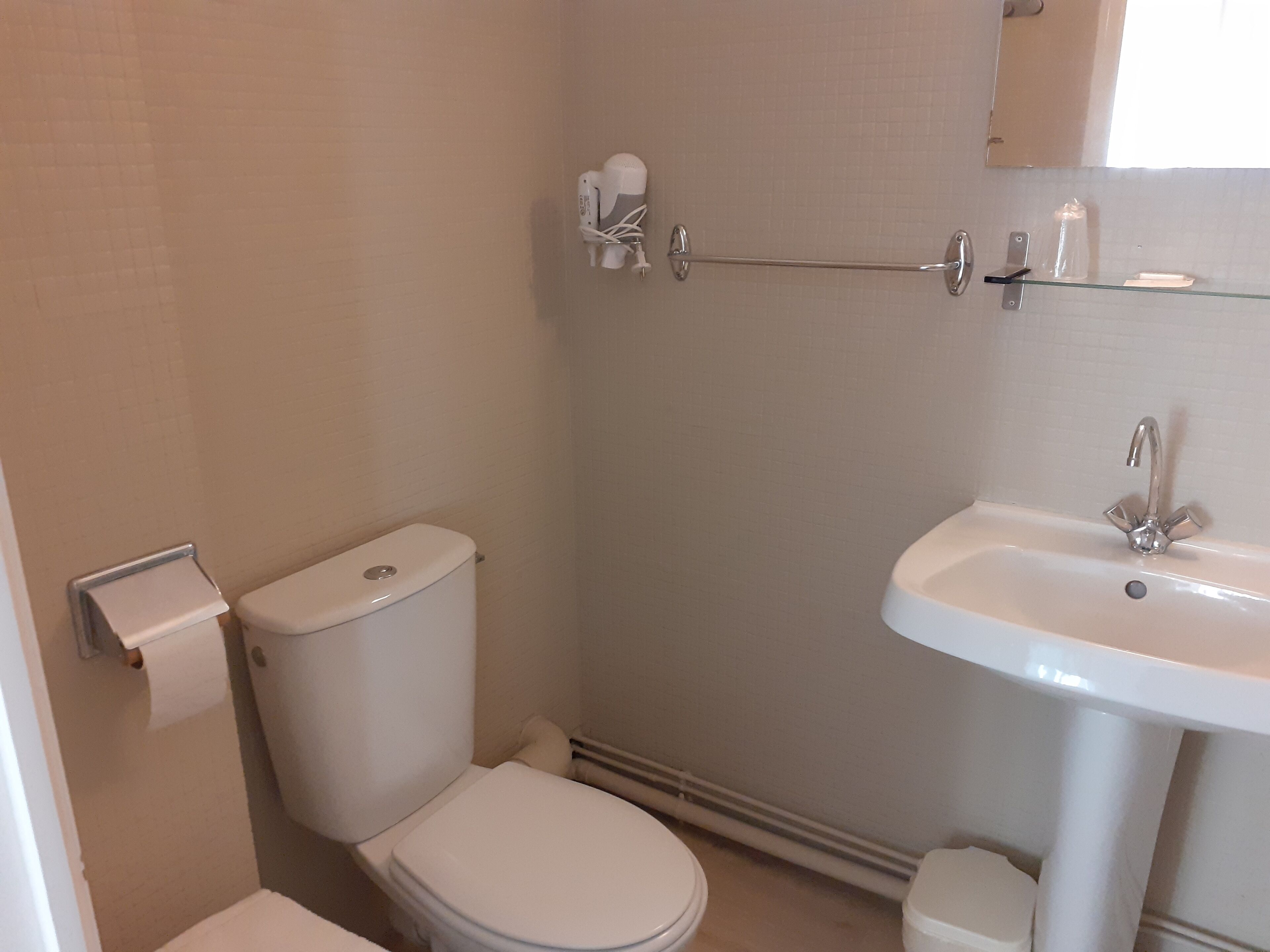 A bathroom with a toilet, a sink, and a towel rack.
