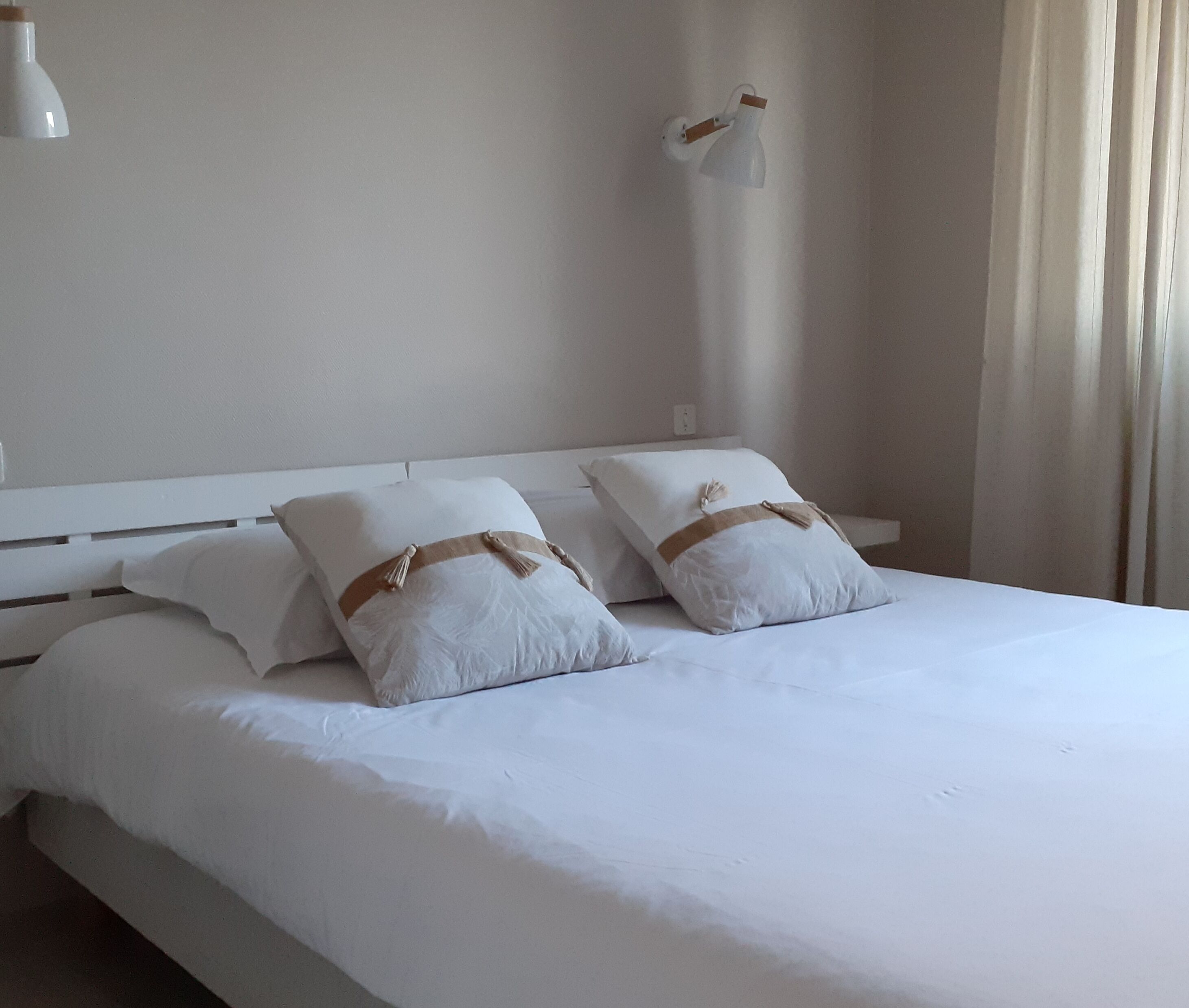 A neatly made bed with white bedding and two pillows with brown accents.