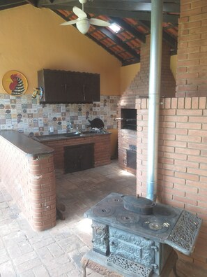 Cozinha com forno de tijolos, ventilador de teto e painel de azulejos.