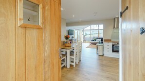 A wooden door leading into a kitchen with a dining area, a large window, and a view of the outdoors. - 2 bedroom accommodation in Llantilio Pertholey (Llantilio Pertholey)