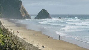 Ein Strand mit felsigen Klippen und einer großen Felsformation in der Ferne.