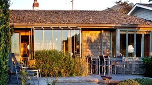 Ein Haus mit einer Terrasse, einem Bücherregal und einem Esstisch mit Stühlen.