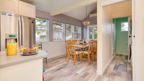A kitchen with a dining area, wooden chairs, a table, and a sign that reads "EAT. SLEEP. SURF."
