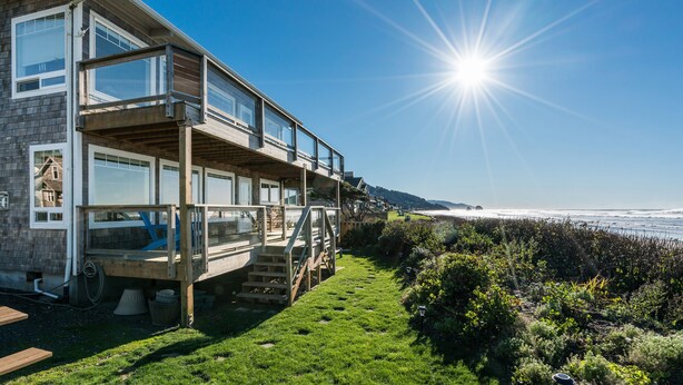 Una casa moderna de dos pisos con un balcón que da a la costa.