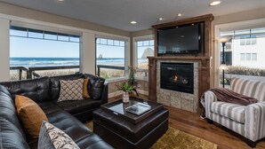 Una sala de estar con un sofá de cuero, un sillón a rayas, una chimenea y un televisor grande.