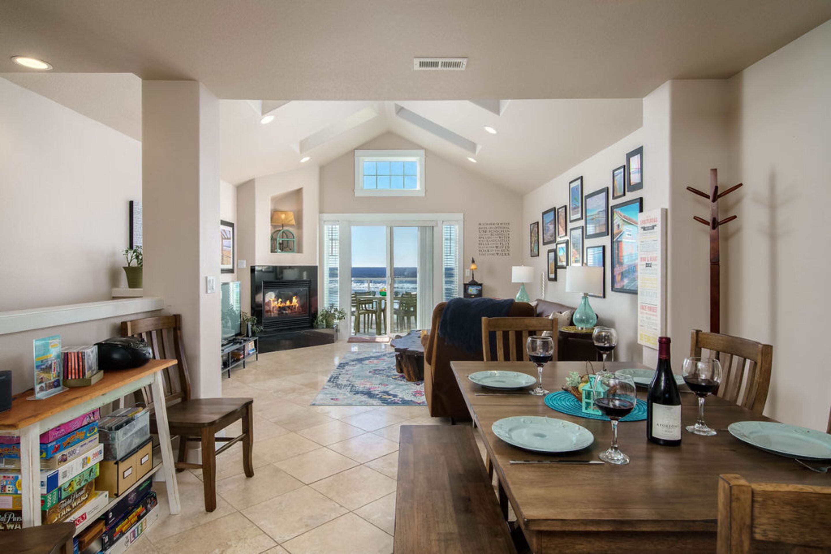 A spacious dining area with a high ceiling, a fireplace, and a view through a glass door.