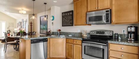A modern kitchen with wooden cabinets, stainless steel appliances, and a granite countertop.