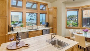 Una cocina moderna con armarios de madera, una isla grande con un lavamanos y vistas al exterior.