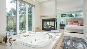 Une salle de bain spacieuse avec une grande baignoire, une cheminée et une vue sur l’extérieur.