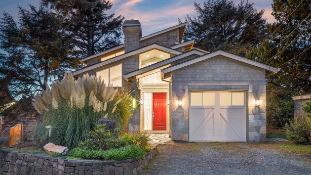 Une maison moderne avec une façade en pierre, une porte rouge et un garage.