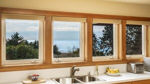 Eine Küche mit einem großen Fenster zum Meer, einer Spüle und einem Toaster.