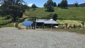 A house with a pond, surrounded by a gravel path and greenery.