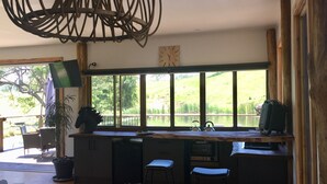 A kitchen with a large window, wooden cabinets, and two bar stools.