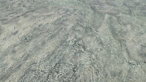 Una spiaggia con acque basse e terraferma in lontananza, ben visibile.