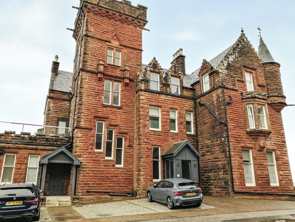 A large, historic brick building with multiple windows and a prominent tower.