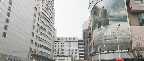 A cityscape with modern buildings, including a prominent white building with a sign that reads "Human Cultural Hall."