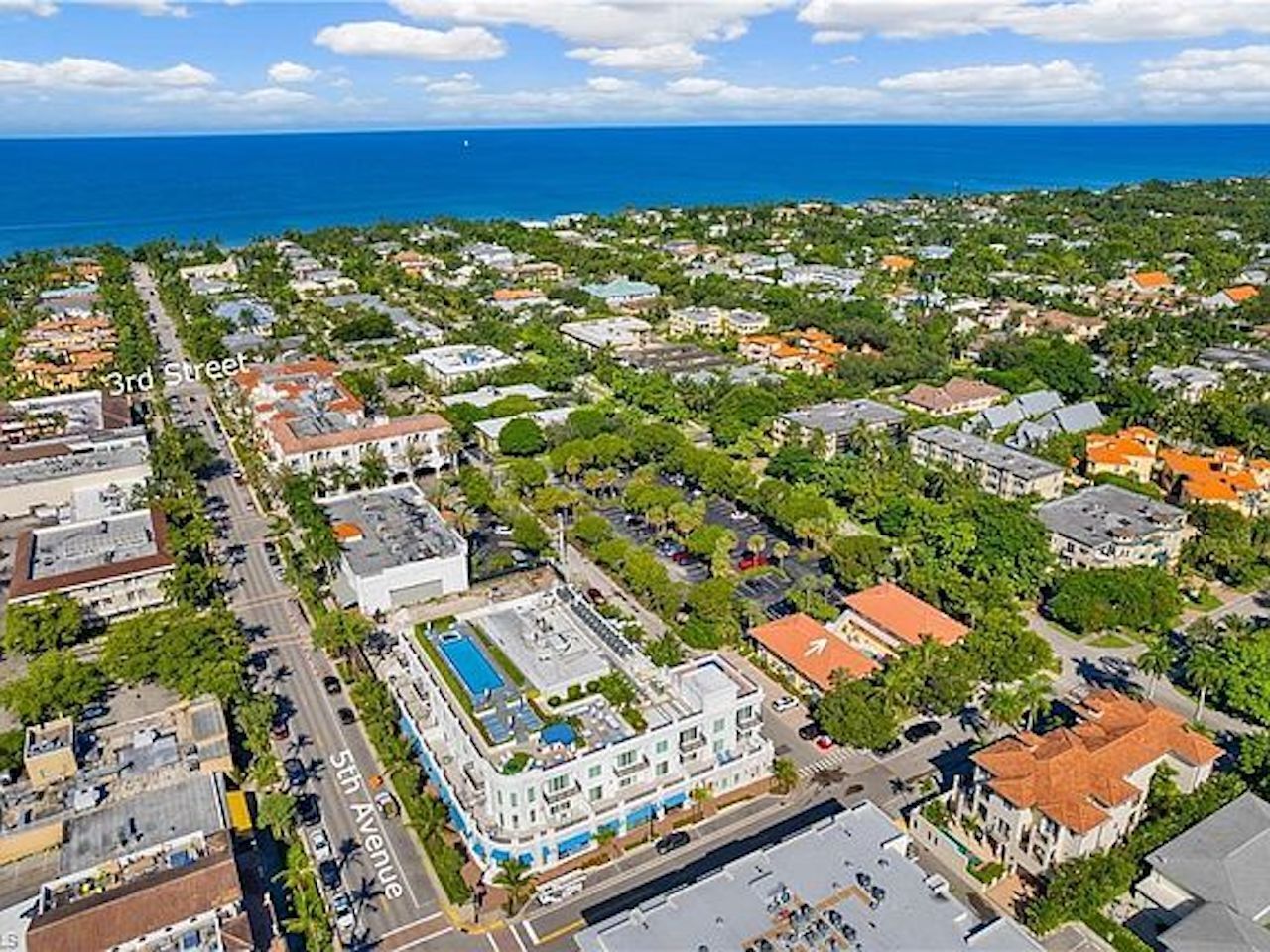 An aerial view of a residential area with a large building featuring a swimming pool and multiple stories.