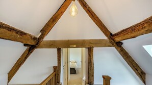 A wooden staircase with a light fixture above, leading to a room with a bed and a door. - Buckley Farm, Barn 1 - UK36588 (Oswestry)