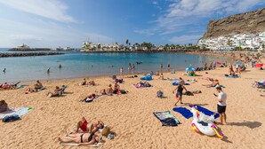 A crowded beach with people sunbathing and swimming.