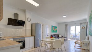 A modern kitchen with a refrigerator, stove, and dining area with chairs and a table.
