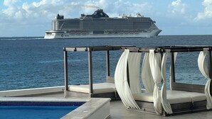 Een zwembad met zicht op een cruiseschip in de verte.