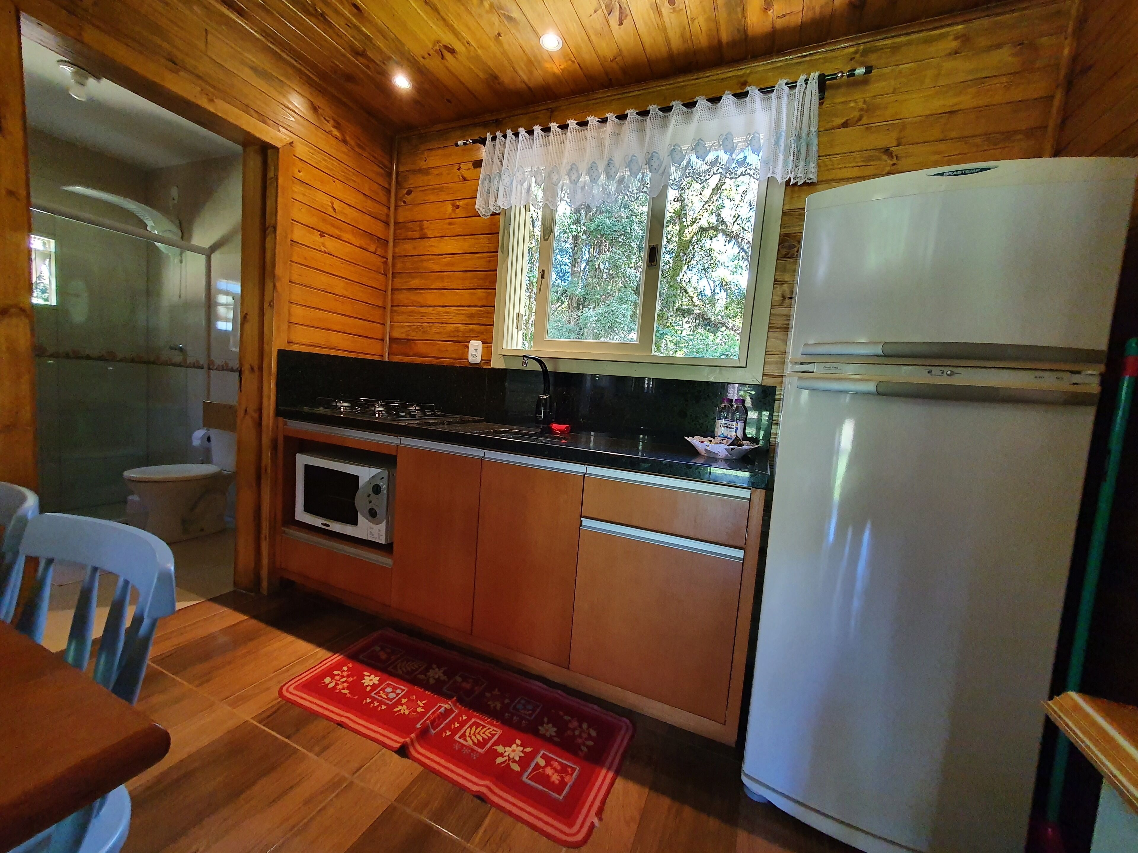 A compact kitchen with wooden cabinets, a microwave, a stove, and a refrigerator.