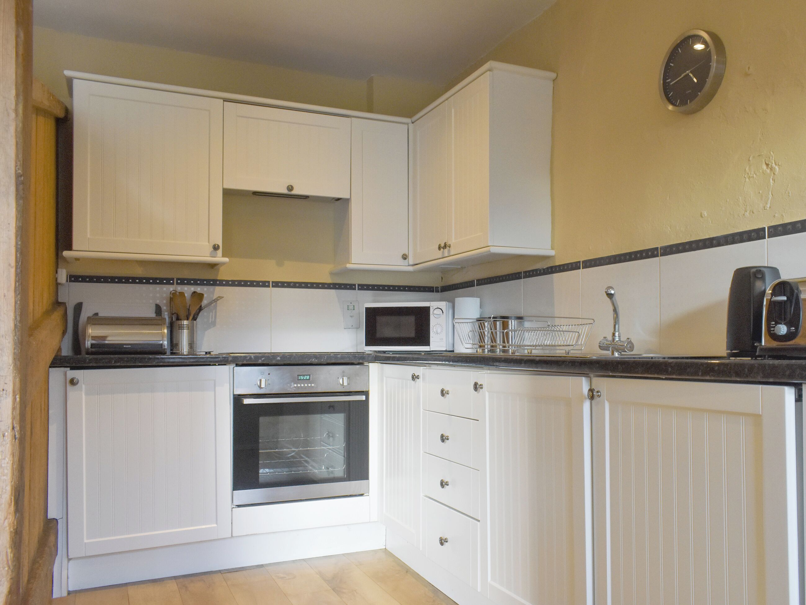 A kitchen with white cabinets, a microwave, an oven, and a toaster.