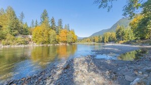 Ein Fluss mit klarem Wasser, umgeben von Bäumen und Bergen.