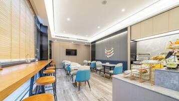 A modern hotel room with a wooden bar, seating area, and a kitchen counter.
