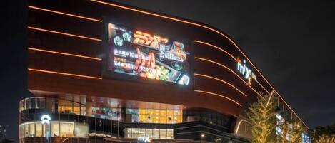 A modern building with a large illuminated sign, glass facade, and a curved design.