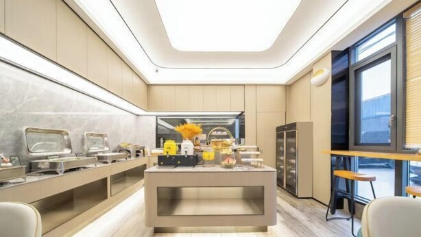 Une chambre d’hôtel moderne dotée d’un buffet central, d’une grande fenêtre et d’un coin salon avec vue.