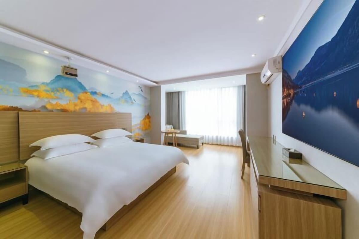A modern hotel room with a large bed, a desk, and a wall-mounted TV.
