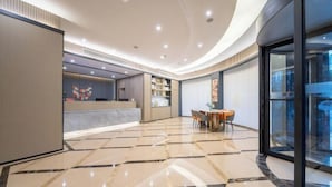 Un hall d’hôtel moderne doté d’un plafond incurvé, d’un comptoir d’accueil, d’un espace salon avec des fauteuils et d’un mur en verre offrant une vue panoramique.