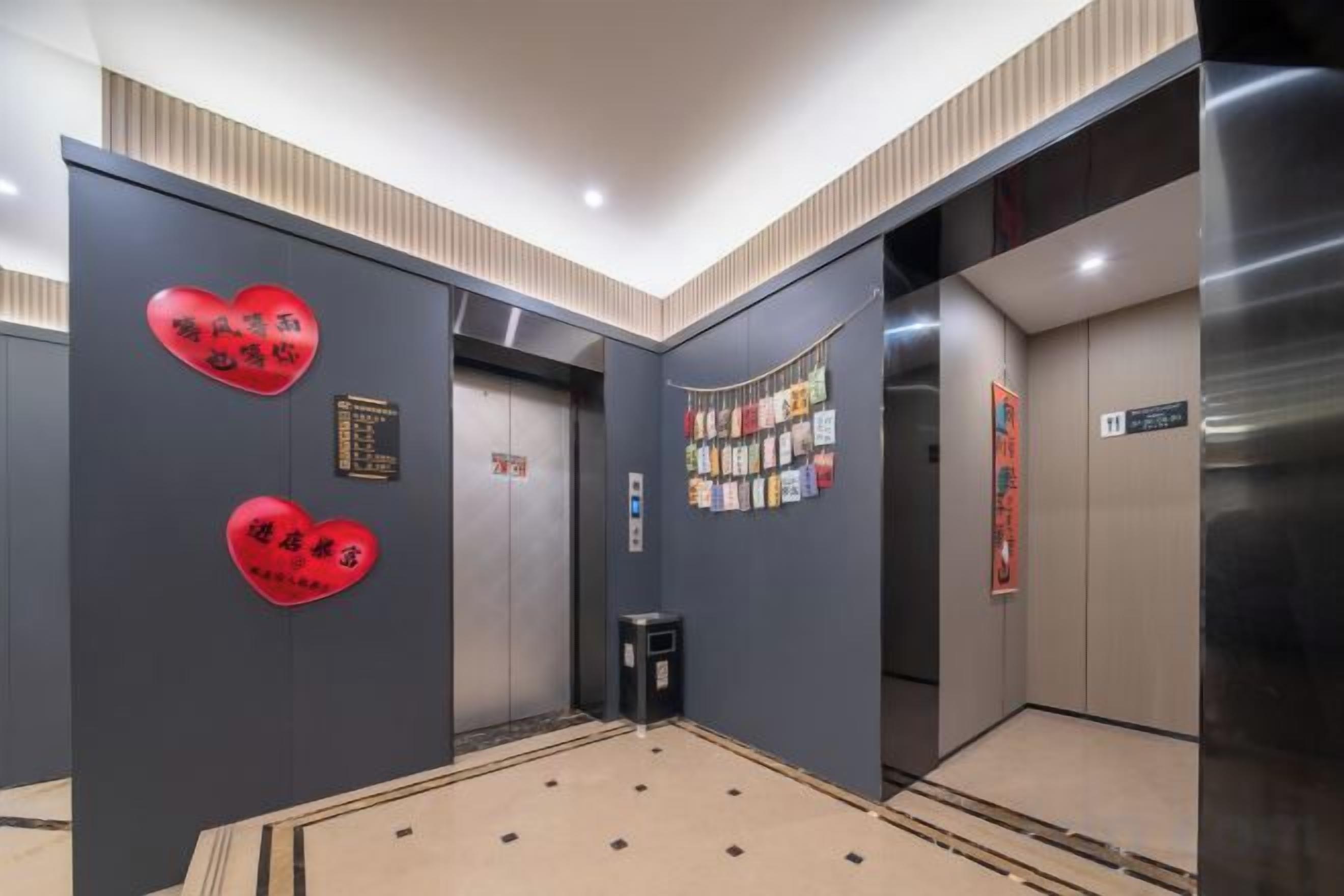 An elevator interior with a patterned floor, a trash bin, and a wall with red heart-shaped decorations.
