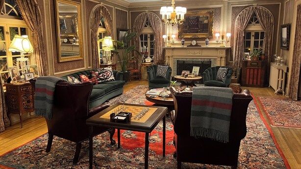 A traditional living room with a fireplace, green sofas, a chess table, and ornate decor. - Pendleton House Historic Inn and B&B (Pendleton)