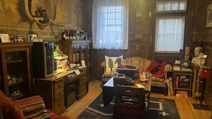 A cozy room with a wooden cabinet, a television, a sofa, and a dining table. - Pendleton House Historic Inn and B&B (Pendleton)