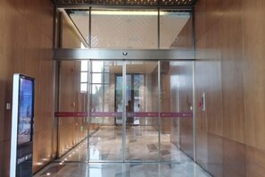 A modern elevator with glass doors, a digital display, and a wooden wall. - Kaluowei Apartment (Zheshang Building) (Dongguan)