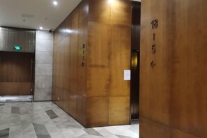 A hallway with a wooden wall and a tiled floor. - Kaluowei Apartment (Zheshang Building) (Dongguan)