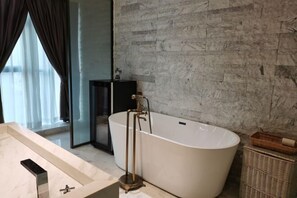 A modern bathroom with a freestanding bathtub, a large mirror, and a marble countertop.