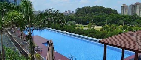 A rooftop swimming pool with a view of a cityscape and greenery.