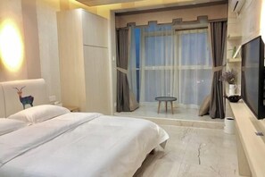 A hotel room with a bed, a TV, a small table, and a window with curtains.