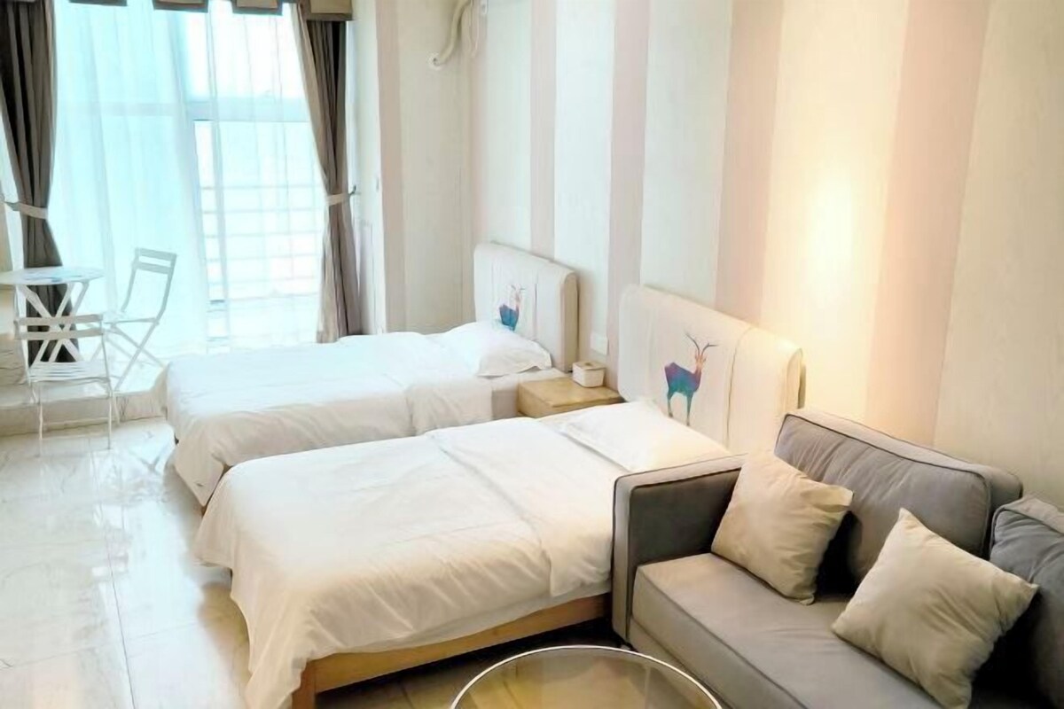 A hotel room with two beds, a sofa, a small table, and a chair.