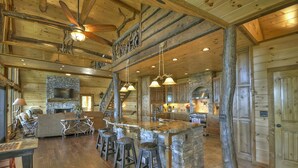 A spacious log cabin interior with a central island bar, stone fireplace, and a cozy seating area. - The VUE Over Blue Ridge - Blue Ridge (Blue Ridge)