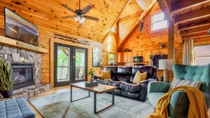 L’intérieur chaleureux d’un chalet en bois, avec une cheminée en pierre, un canapé en cuir et un coin repas.
