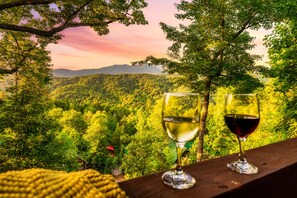 Two wine glasses on a wooden ledge with a view of a forest and mountains. - Stunning Views! Fall Sale! Hot Tub, Pool Table, Arcade (Gatlinburg)