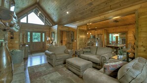 Ein geräumiges Blockhaus-Interieur mit hohen Decken, Holzwänden und einer gemütlichen Wohnbereich mit Ledersofas und einem Esstisch.