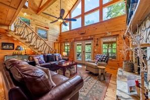 A spacious wooden cabin with a large living area, a staircase, and a view of the outdoors. - The Loose Caboose - Blairsville, GA (Blairsville)